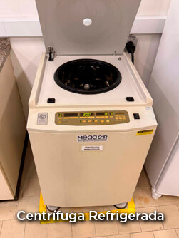 Dois homens em um laboratório de engenharia, um aponta para um painel de controle complexo com fios.