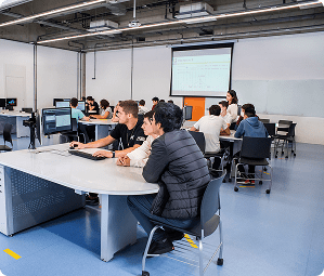Sala de aula moderna com alunos e professor em frente a um projetor no Instituto Mauá de Tecnologia.