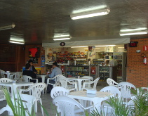 Cantina do Instituto Mauá de Tecnologia com mesas e cadeiras plásticas, balcão e pessoas.
