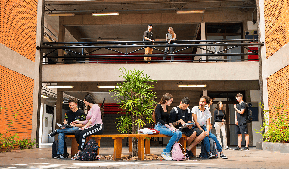Alunos do Instituto Mauá de Tecnologia sentados em um banco da instituição