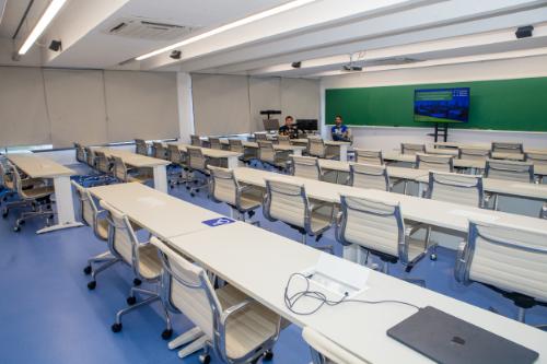 Sala de aula moderna do Instituto Mauá de Tecnologia com mesas e cadeiras, tela na parede.