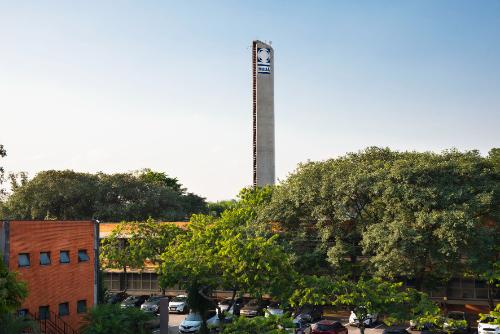 Torre com logo do Instituto Mauá de Tecnologia em dia ensolarado, com prédios e árvores ao redor.