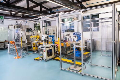 Laboratório com robôs industriais, máquinas e equipamentos em um ambiente de pesquisa e desenvolvimento.