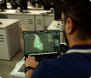 Homem projeta modelo 3D em laptop em sala de aula do Instituto Mauá de Tecnologia.