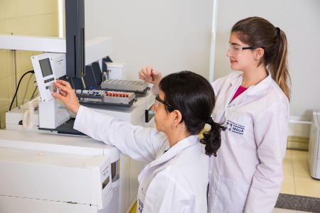 Duas mulheres em jalecos brancos trabalham em um equipamento de laboratório no Instituto Mauá de Tecnologia