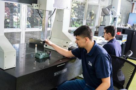 Estudante do Instituto Mauá de Tecnologia opera máquina de medição de precisão em laboratório.