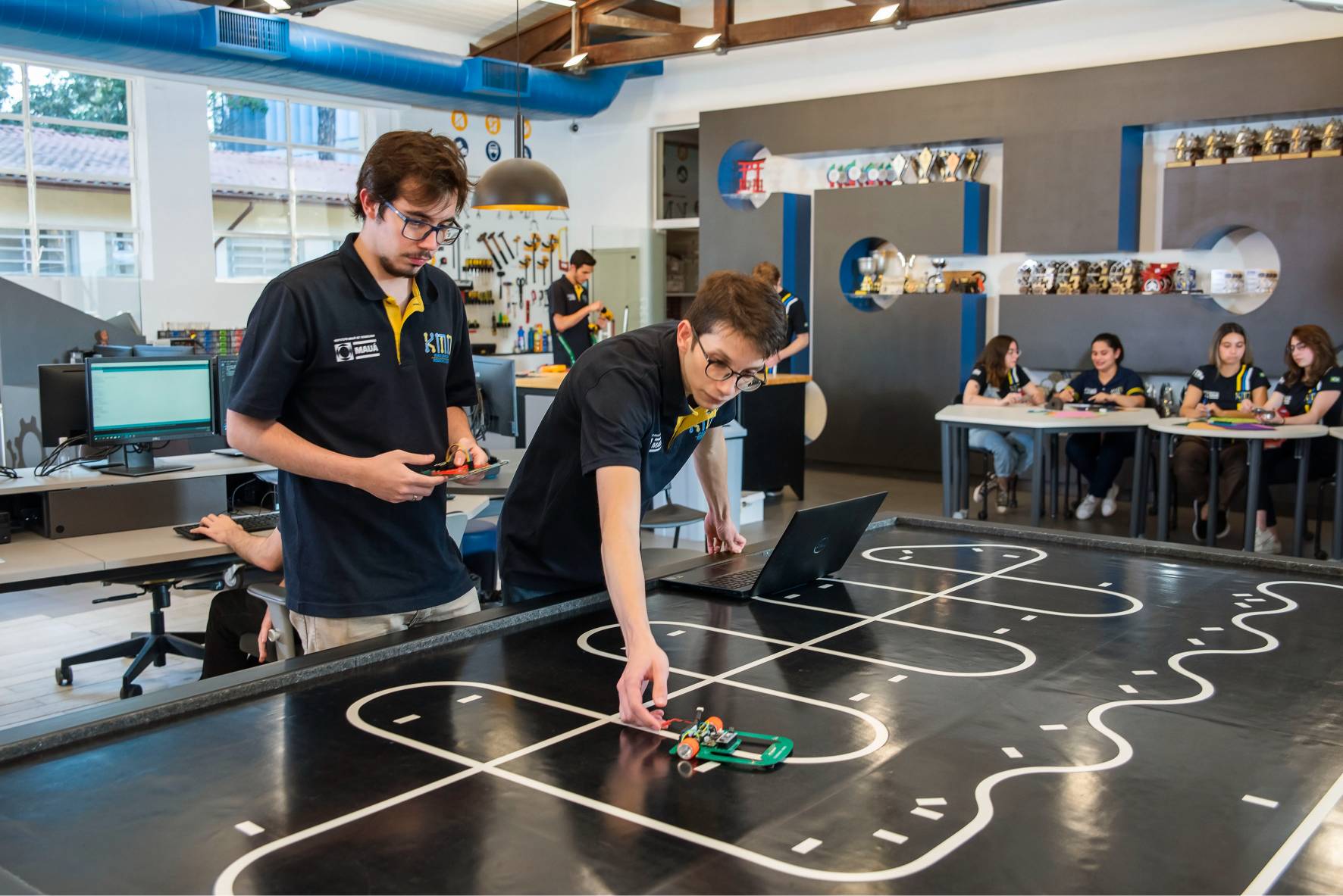 Estudantes do Instituto Mauá de Tecnologia testam robô em pista com laptop.