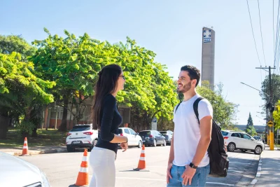 Duas pessoas conversando em frente à torre do Instituto Mauá de Tecnologia em um dia ensolarado.