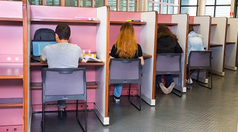 Estudantes estudam em cabines individuais em uma biblioteca.